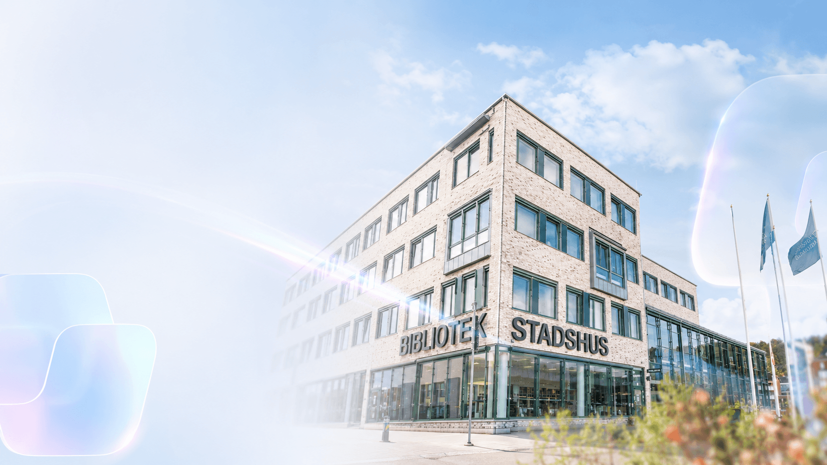 Bibliotekets och stadshusets ljusa fasad i klart dagsljus, med mjukt prismaljus i förgrunden.